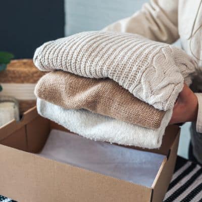 Clothes being placed into a box ready to be donated.